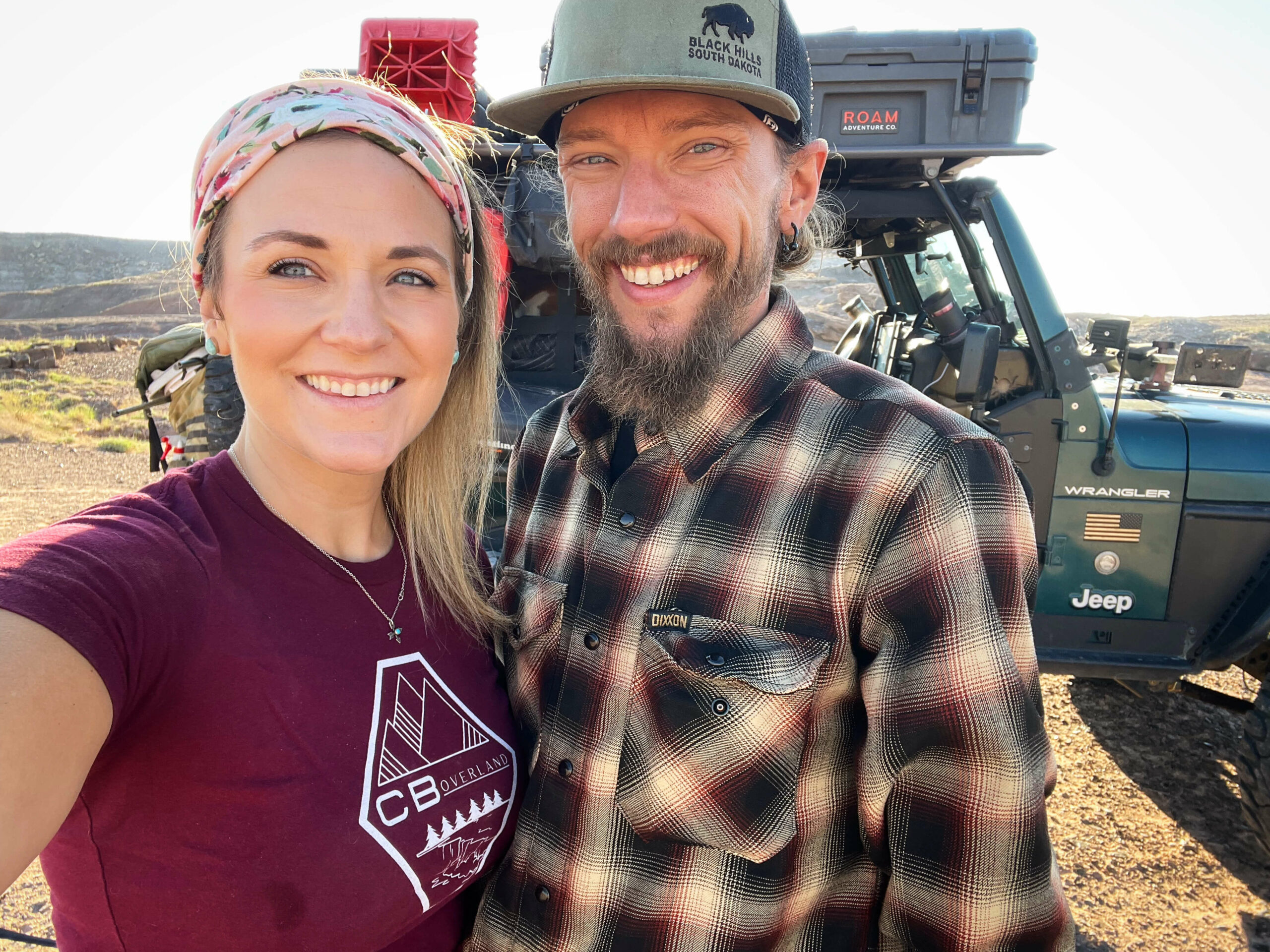Chelsea and Blake stand in front of their overlanding jeep.