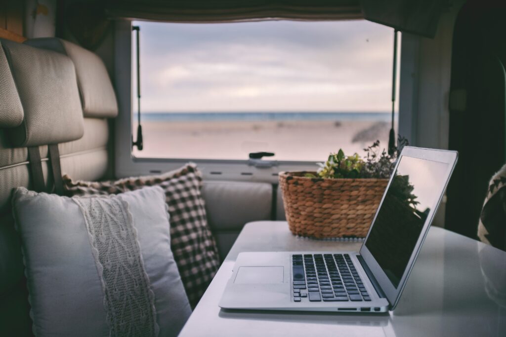 Computer on a desk in an RV overlooking the ocean.