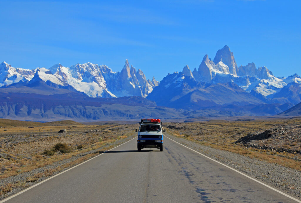 A solo vanagon on an empty road with mountains in the background.