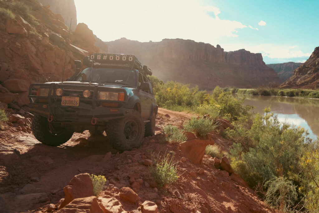 An overland vehicle sits on a trail next to a river