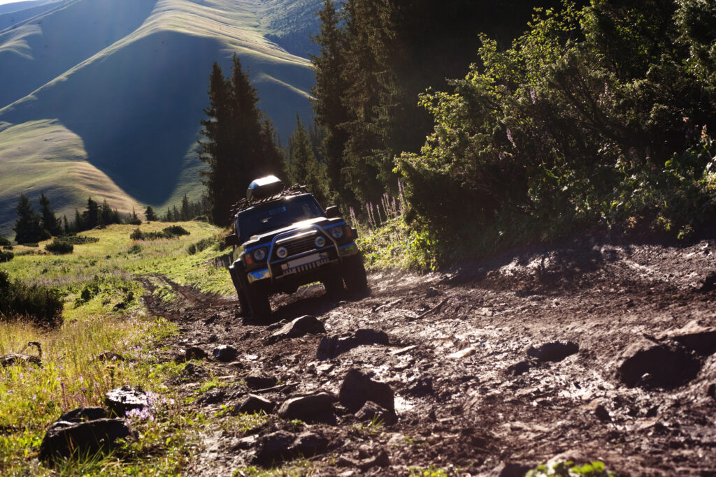 An overland vehicle treks uphill across a rocky terrain